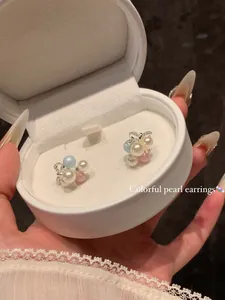 Detailed macro view of colorful grape-shaped pearl stud earrings in a white gift box