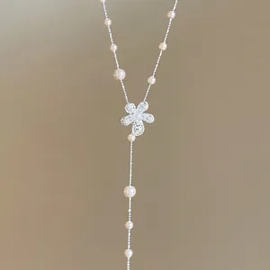 Nahaufnahme von funkelndem Blumenanhänger und weißer Perlen-Quastenkette
