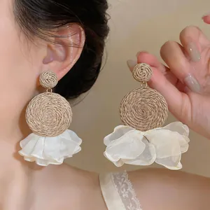 Detail of Bohemian raffia earrings with delicate white chiffon ruffles