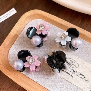 Eleganti mini fermagli per capelli con fiori di strass e perle su vassoio di legno