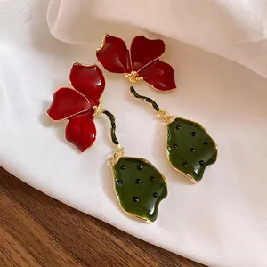 Elegant retro red flower and green leaf oil-drop earrings on white silk fabric