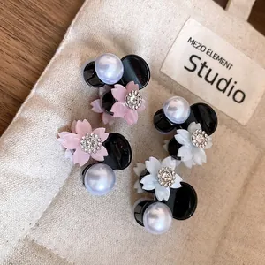 Eleganti mini fermagli per capelli con fiori di strass e perle su sfondo di tela