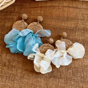 Close-up of Bohemian raffia earrings with delicate blue and cream chiffon petals