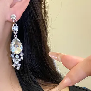 Close-up of elegant water-drop crystal dangling earrings worn on a model's ear