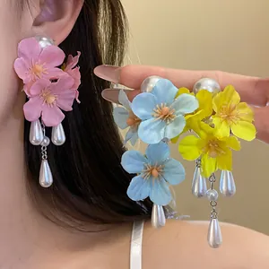 Detailed view of colorful fabric flower tassel earrings with pearls shown on model