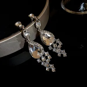 Macro shot of sparkling silver-toned drop earrings featuring teardrop crystals and pavé stones.