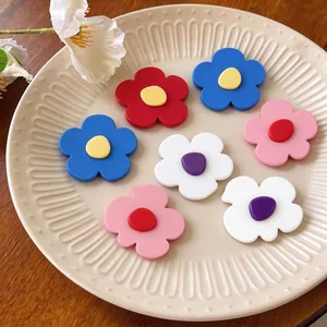 Set of colorful geometric flower hair clips on a decorative plate for hair styling
