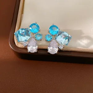 Dettaglio di orecchini a lobo in argento con zirconi blu e pietre trasparenti