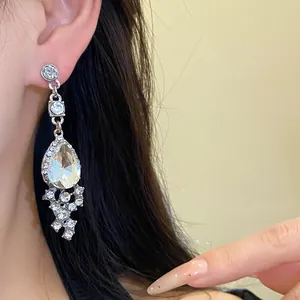 Detail view of elegant teardrop earrings with crystals worn by a model on dark hair