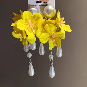 Detailed view of yellow fabric flower tassel earrings with elegant white faux pearls.