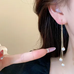 Elegant 18K gold plated long tassel earrings with pearls detail shot on model's ear