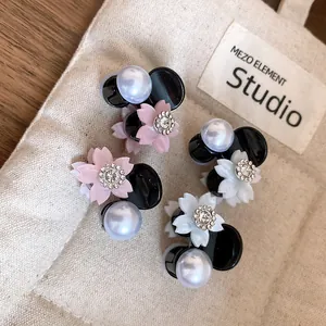 Primo piano di eleganti mini fermagli per capelli a fiore con perle e strass su tela