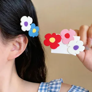 Detailed macro view of colorful geometric flower hair clips on model and display card