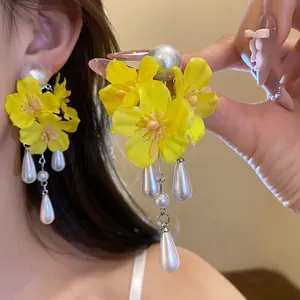 Detailed macro shot of yellow fabric flower earrings with elegant hanging white pearl tassels
