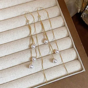 Close-up detail of elegant 18k gold plated long tassel pearl earrings in a jewelry box