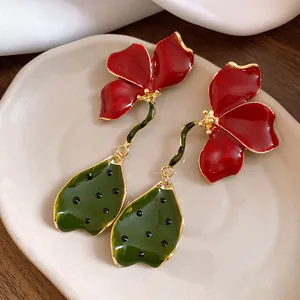 Detailed shot of vintage enamel flower drop earrings with red petals and green leaves