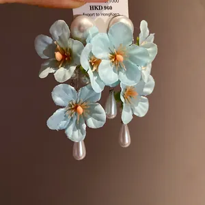 Close-up of light blue fabric flower earrings with elegant teardrop pearl tassels