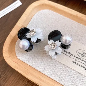Dettaglio di mini mollette per capelli con fiore in resina, strass e perla bianca.