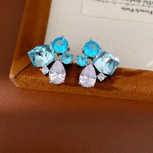 Primo piano dettagliato di orecchini a lobo geometrici con zirconi blu e trasparenti