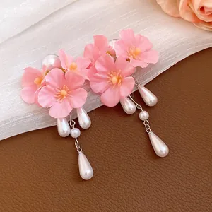 Close-up detail of pink cherry blossom flower earrings with elegant white pearl tassels.