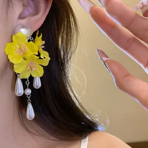 Macro view of vibrant yellow flower tassel earrings with pearls on an Asian model