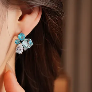 Primo piano dettagliato di eleganti orecchini in zircone azzurro indossati dal modello