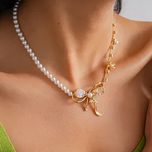 Detailed view of asymmetrical faux pearl and gold bow necklace with zircon bee and resin flower