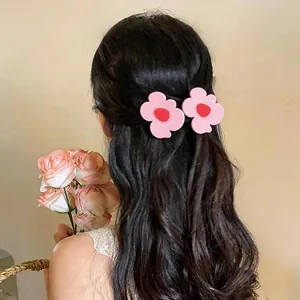 Back view of a woman wearing pink flower-shaped duckbill hair clips on wavy hair