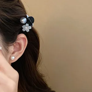 Dettaglio ravvicinato di mini molletta con perla e fiore di strass su capelli castani