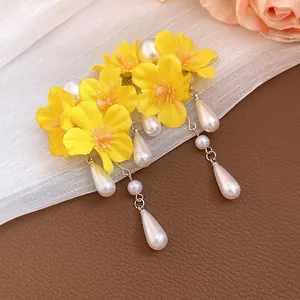 Exquisite detail of yellow floral tassel earrings with white pearls on elegant background