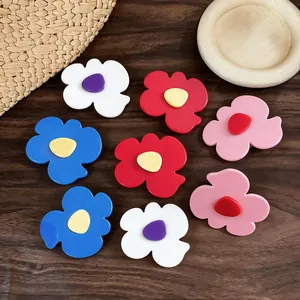 Detailed view of colorful geometric flower-shaped duckbill hair clips on wooden background