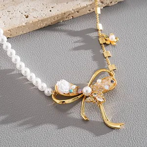 Detailed macro view of a pearl and gold bow necklace with zircon bee and resin flower accents.