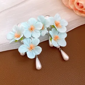 Close-up of elegant light blue floral tassel earrings with white pearl drop pendants