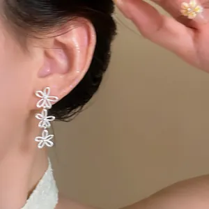 Detailed close-up view of silver hollow flower tassel earrings worn on a model ear