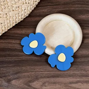 Detailed macro shot of blue flower hair clips with cream centers on a wooden tray