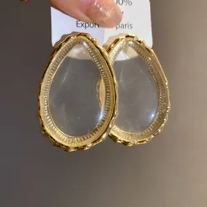 Dettaglio orecchini vintage in resina a goccia con eleganti bordi smerlati color oro