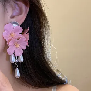 Close-up of pink fabric flower earrings with elegant pearl tassels on a model