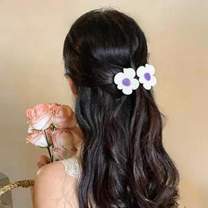 Detailed close-up view of white flower hair clips with purple centers on wavy dark hair