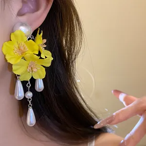Close-up of bright yellow fabric flower tassel earrings with pearl drops
