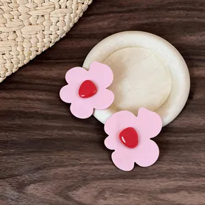 Detailed macro view of pink flower hair clips with red center on rustic wooden background