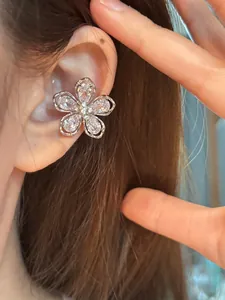Gros plan d'un délicat protège-oreille en argent en forme de fleur avec zircone sur une oreille