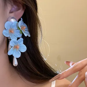 Detailed view of blue fabric flower earrings featuring large white pearl studs and teardrop dangles