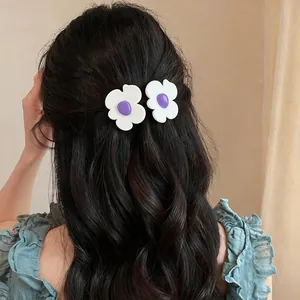 Macro view of white flower hair clips with purple centers clipped in dark wavy hair