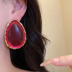 Dettaglio di eleganti orecchini vintage in resina rossa a goccia con bordo dorato