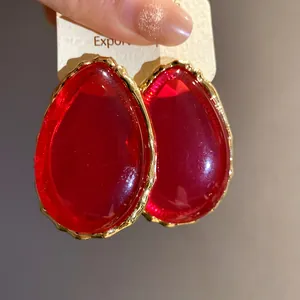 Primo piano di orecchini vintage a goccia in resina rossa con bordi oro