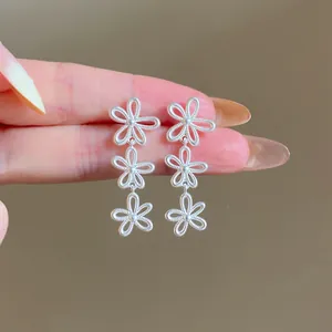 Close-up of elegant silver tiered flower tassel earrings with intricate textured details.