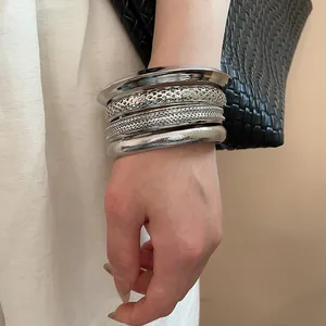 Close-up macro view of textured silver metallic bangles and mesh bracelets on wrist