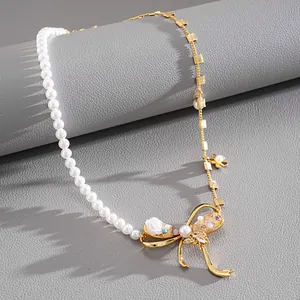Detailed view of pearl and gold chain necklace with intricate bow and flower charms.
