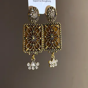 Primo piano di orecchini vintage quadrati con filigrana dorata e cristalli luce