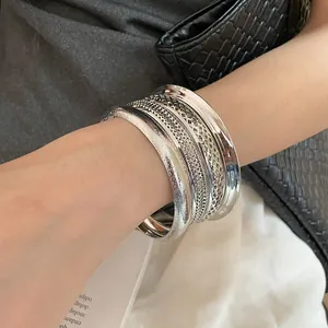 Close-up of stylish silver multi-textured bracelets on wrist with mesh and matte details